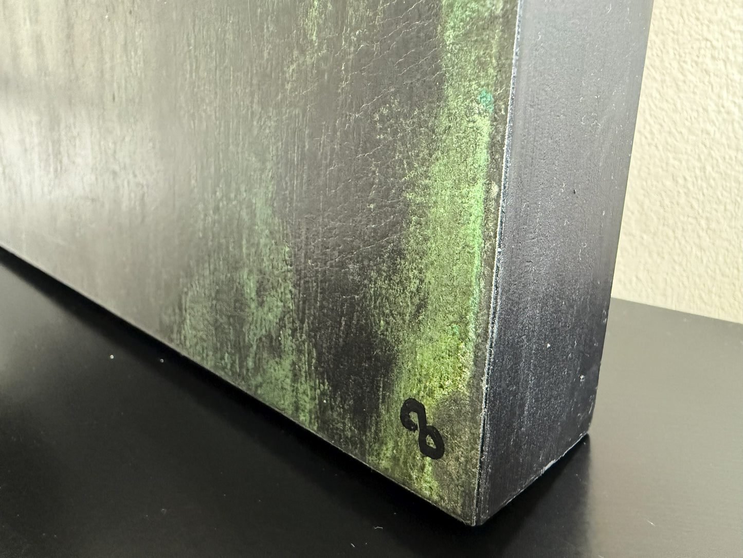 Bottom corner of Carrie Bergey's 'Through' painting featuring artist's CB signature and textured green-black finish on canvas edge.