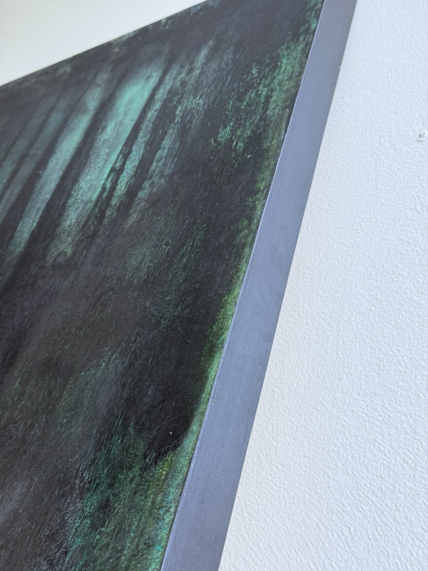 Angled detail of Carrie Bergey's original painting showing edge texture and layered green-black tones on canvas panel.